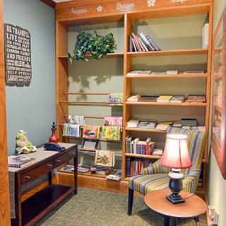 A cozy reading nook with wooden shelves filled with books and a comfortable armchair.