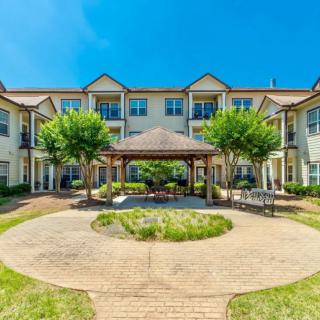 A residential building with a landscaped courtyard featuring a central gazebo and pathway.