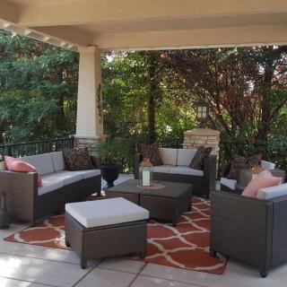 A cozy outdoor seating area on a covered patio, featuring comfortable rattan furniture and a vibrant rug.