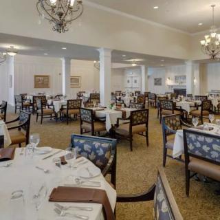 A spacious dining room with elegantly set tables and chandeliers.