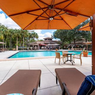 Chairs and umbrellas surround a serene outdoor swimming pool, perfect for relaxation.