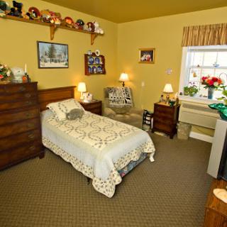 A cozy and inviting bedroom featuring warm yellow walls, a neatly made bed, and charming decorative items.