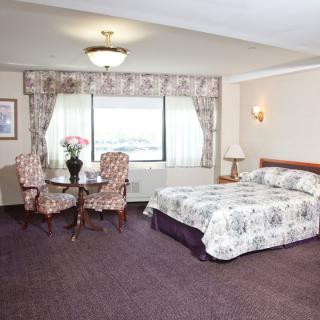 A cozy hotel room with a double bed and seating area by the window.