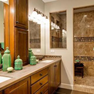 A well-designed bathroom featuring wood cabinets, a large mirror, and decorative green jars on the vanity.