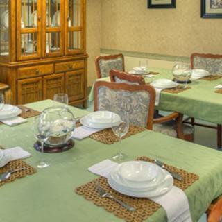 A well-set dining room table with a green tablecloth and elegant dinnerware.