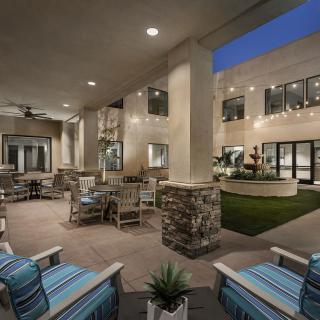 An inviting outdoor patio area illuminated in the evening, featuring comfortable seating and elegant lighting.