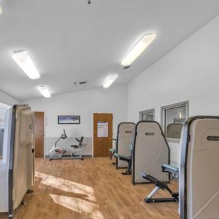 A clean and well-lit gym with exercise equipment lined up against the walls.