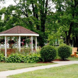 A peaceful park scene featuring a gazebo surrounded by lush greenery and a winding pathway.
