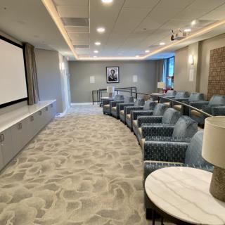 A modern conference room with organized seating and a projector screen, designed for meetings and presentations.