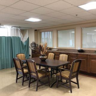 A hospital dining area with a table, chairs, and privacy curtains.
