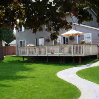 A house with a spacious backyard featuring a wooden deck, green lawn, and a winding pathway.