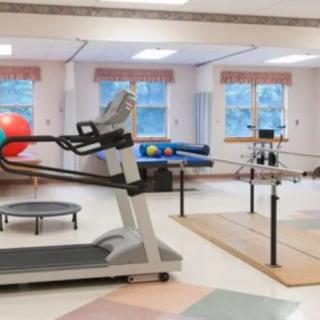 A rehabilitation center gym with exercise equipment including a treadmill and exercise balls.