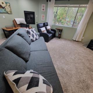 A cozy living room with a large sofa and recliner facing a window.