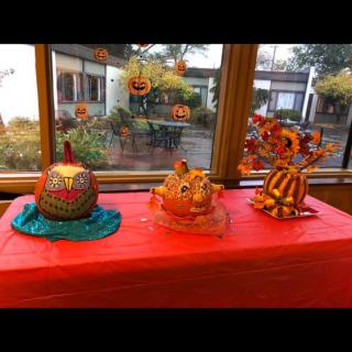 A festive display of decorated pumpkins for Halloween on a red tablecloth.