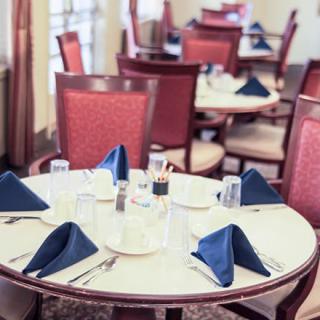 A neatly set restaurant table with blue napkins and red chairs.