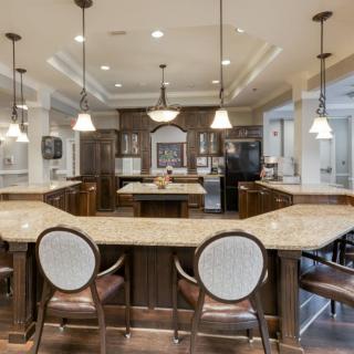 A spacious and modern kitchen with a large central island, pendant lighting, and elegant seating.