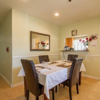 A cozy dining area featuring a neatly set table with chairs and a mirror on the wall.