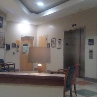 A quiet hospital lobby featuring a cozy waiting area with an elevator in the background.