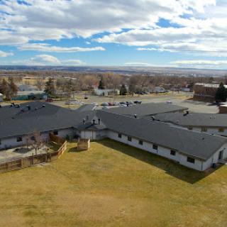 Aerial view of a building complex surrounded by open land and an expansive sky.