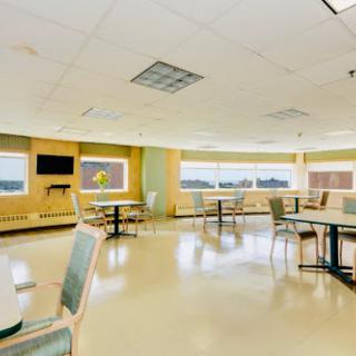 A bright and spacious dining area in a hospital, featuring tables and chairs with large windows offering natural light.