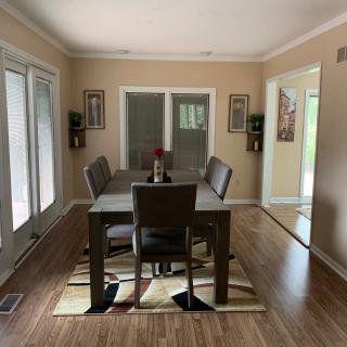 A neatly arranged dining room with a table set, surrounded by chairs and decorated with wall art.
