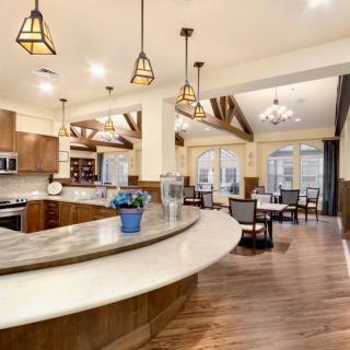 A spacious open-concept kitchen and dining area featuring modern design with wood flooring, pendant lighting, and granite countertops.