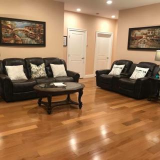 A cozy living room with leather sofas, a wooden coffee table, and decorative paintings on the walls.