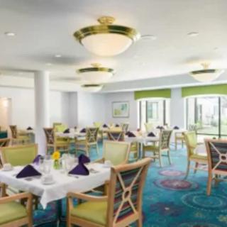 An elegant dining area with well-set tables, featuring natural lighting and stylish decor.