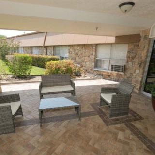 A covered outdoor patio with wicker furniture and a garden view.