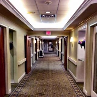 A well-lit hotel hallway with multiple doors and a patterned carpet.