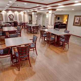 A spacious dining area with neatly arranged tables and chairs, featuring wood flooring and decorative elements.