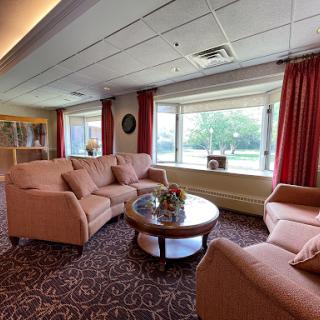 A cozy living room setting featuring comfortable sofas and a coffee table, with natural light streaming in through large windows.