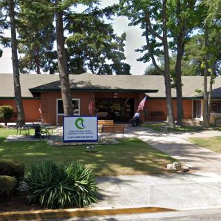 A clinic building surrounded by trees with a sign in front.