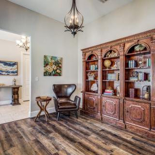 A cozy home library with a wooden bookshelf, a leather chair, and elegant lighting.