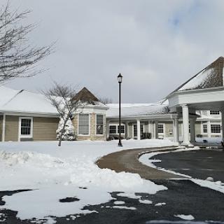 A winter scene featuring a residential building surrounded by snow under a cloudy sky.