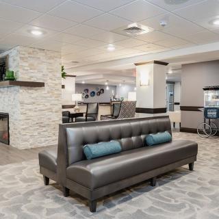 A modern lobby featuring a comfortable seating area with a sofa and decorative pillows.