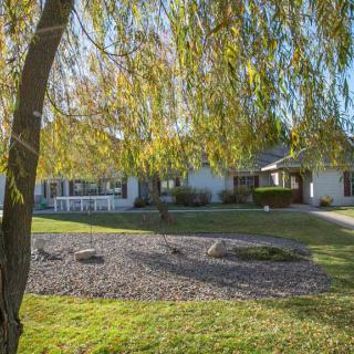 A sunny view of a suburban house with a green yard and trees.