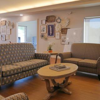 A cozy living room with patterned sofas and a wooden coffee table, decorated with wall art.
