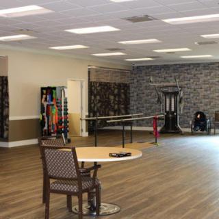 A spacious interior room featuring chairs, exercise equipment, and wooden flooring, designed for community activities.