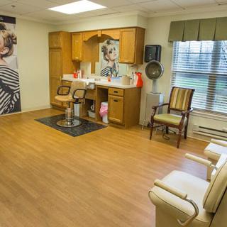 A cozy salon interior with styling chairs and mirrors, featuring wall posters and wooden flooring.