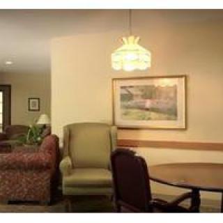 A cozy living room with a sofa, chairs, and a small table under a decorative lamp.