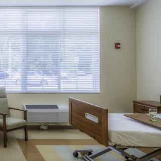 A well-lit hospital patient room featuring a bed and seating area.