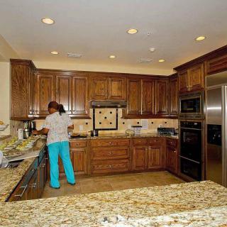 A spacious kitchen with wooden cabinets and granite countertops, featuring modern appliances.