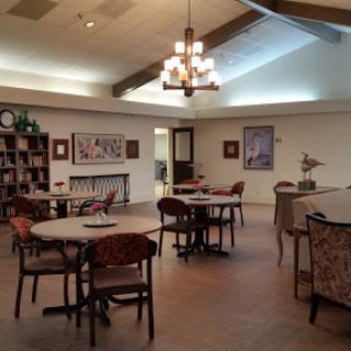 A spacious community lounge with tables, chairs, and decorative artwork, providing a cozy environment for social gatherings.