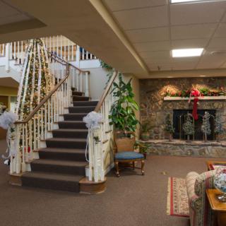 A warmly decorated interior with a staircase and fireplace, featuring holiday decor.