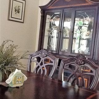 A traditional dining room with a wooden table, ornate chairs, and a china cabinet.