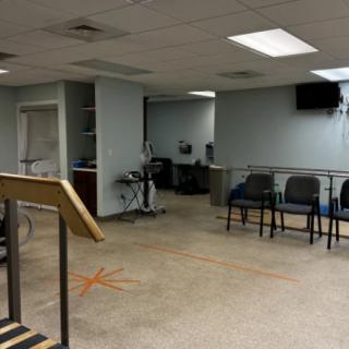 An empty waiting room with a row of chairs and a television on the wall.