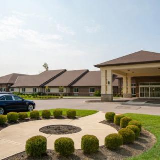 A hotel entrance with landscaped surroundings and a parked car.