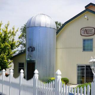 A building with a large metal silo and a white picket fence in the foreground.