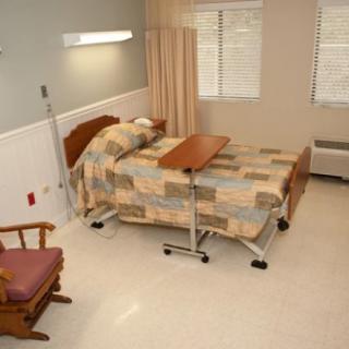A simple hospital room with a bed, side table, and chair.